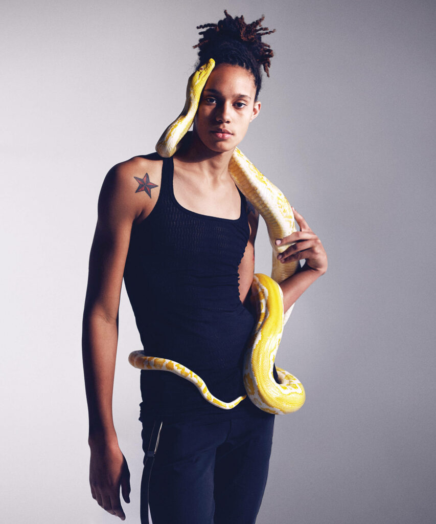 Brittney Griner holding albino python wearing black tank top in studio highlighting strength and elegance Wallpaper