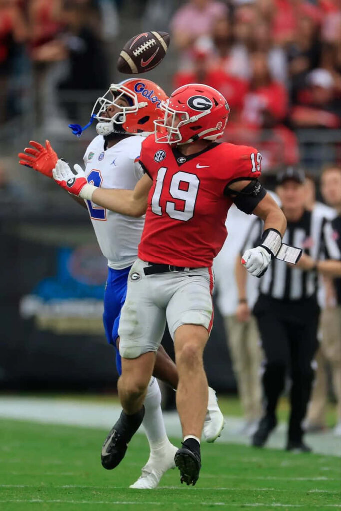 Brock Bowers high-intensity college football catch with vivid team colors and stadium action Wallpaper