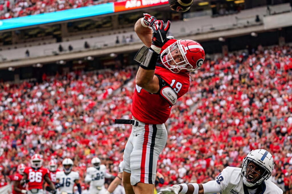 Brock Bowers intense football catch in red and white stadium action high energy sports wallpaper