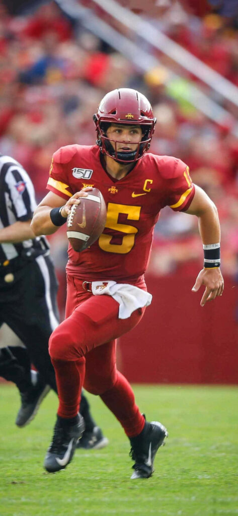 Brock Purdy Iowa State quarterback running with football in red gold uniform stadium background Wallpaper