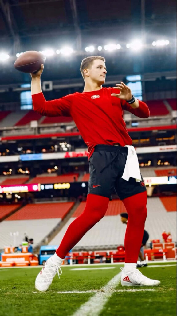 Brock Purdy quarterback warmup in red gear dynamic football action vibrant stadium background wallpaper
