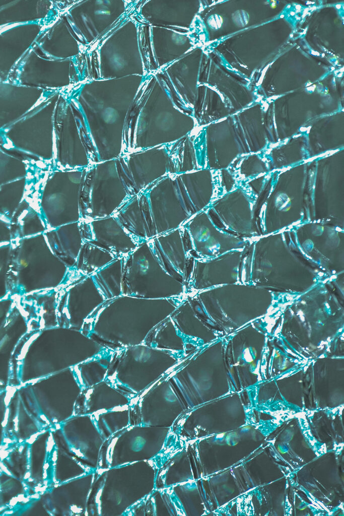 Abstract shattered glass wallpaper with turquoise hues and realistic cracked texture background