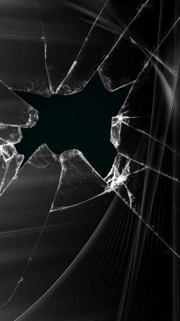 Close-up of shattered glass with central hole sharp edges and intricate monochrome cracks wallpaper