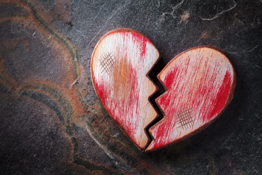 Broken heart wallpaper with cracked surface on dark textured background symbolizing heartache