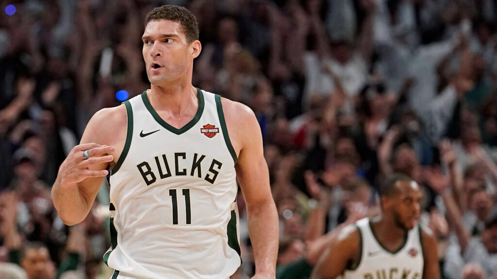 Brook Lopez Milwaukee Bucks in white jersey dominating court action with vibrant crowd background Wallpaper