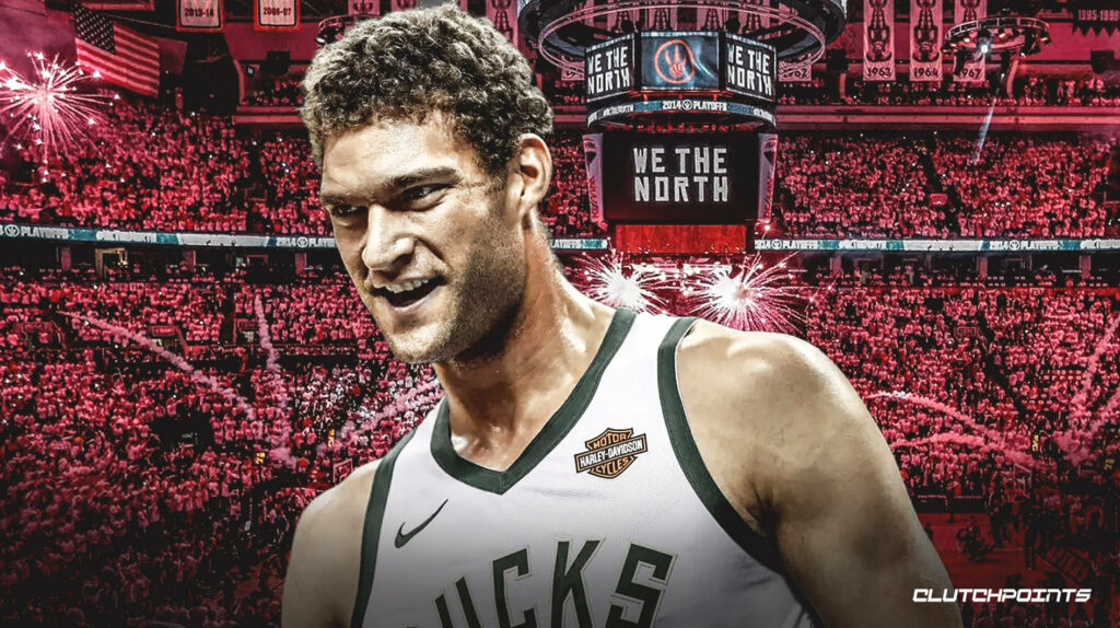 Brook Lopez in Milwaukee Bucks jersey with red arena background and We The North banners Wallpaper