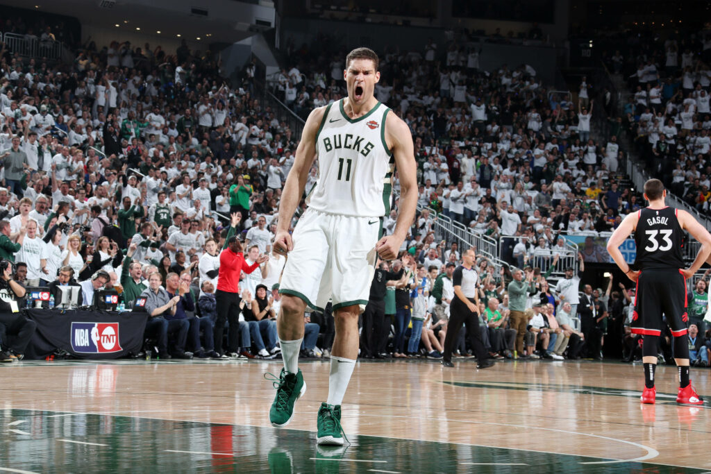 Brook Lopez screaming in celebration on Milwaukee Bucks court with vibrant arena lights and crowd Wallpaper
