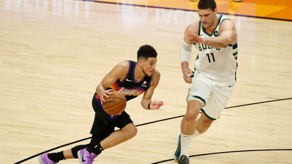 Brook Lopez defends Devin Booker dribbling Phoenix Suns vs Milwaukee Bucks intense NBA action Wallpaper