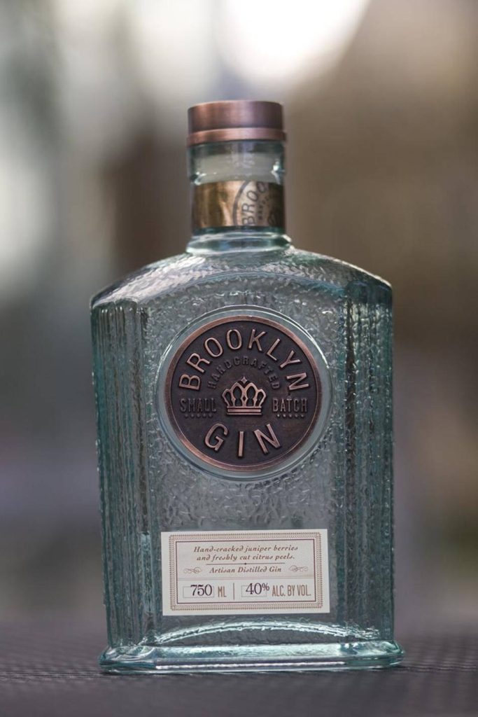 Textured glass Brooklyn Small Batch Gin bottle with copper emblem on blurred background wallpaper