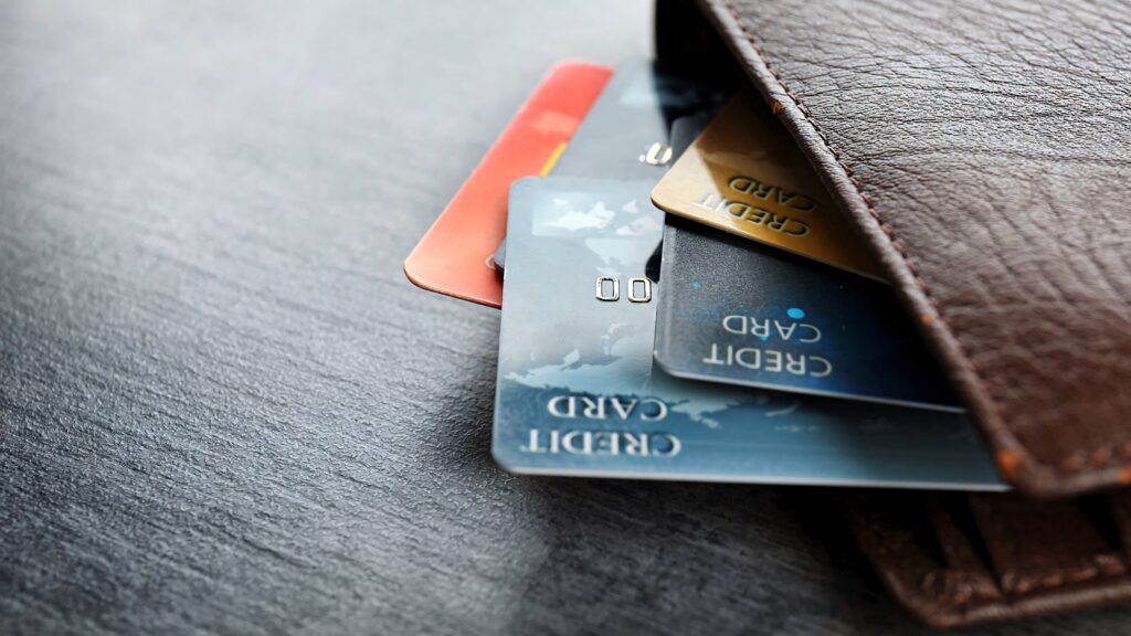 Brown leather wallet with colorful credit cards on dark textured surface modern finance essentials Wallpaper