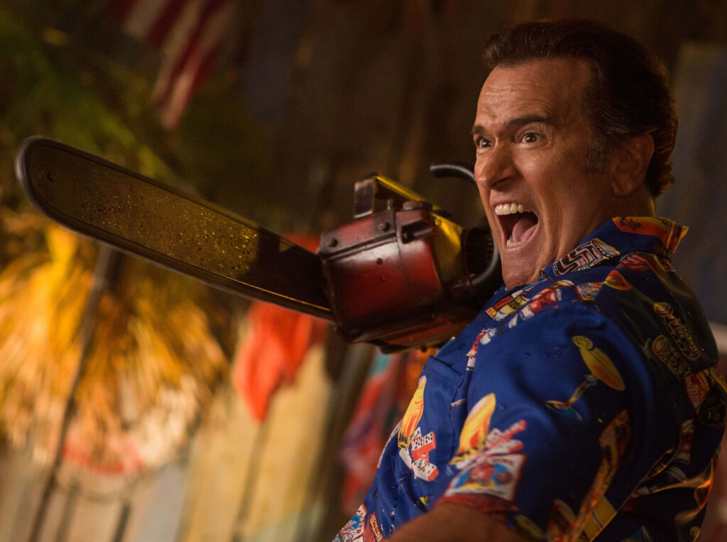 Bruce Campbell in tropical shirt brandishing chainsaw dynamic horror adventure wallpaper background