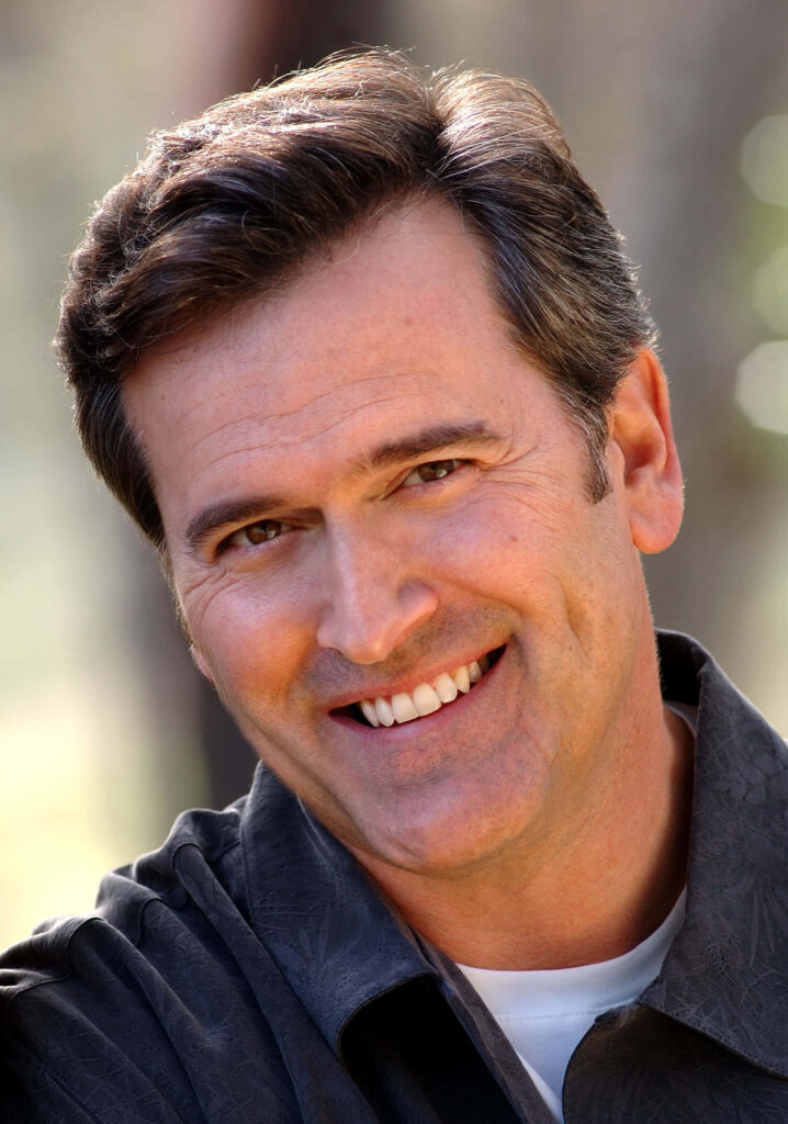 Bruce Campbell close-up portrait warm smile soft lighting blurred outdoor background wallpaper