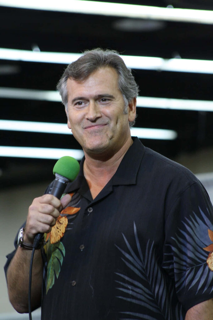 Bruce Campbell holding green microphone candid photo modern indoor striped lighting wallpaper