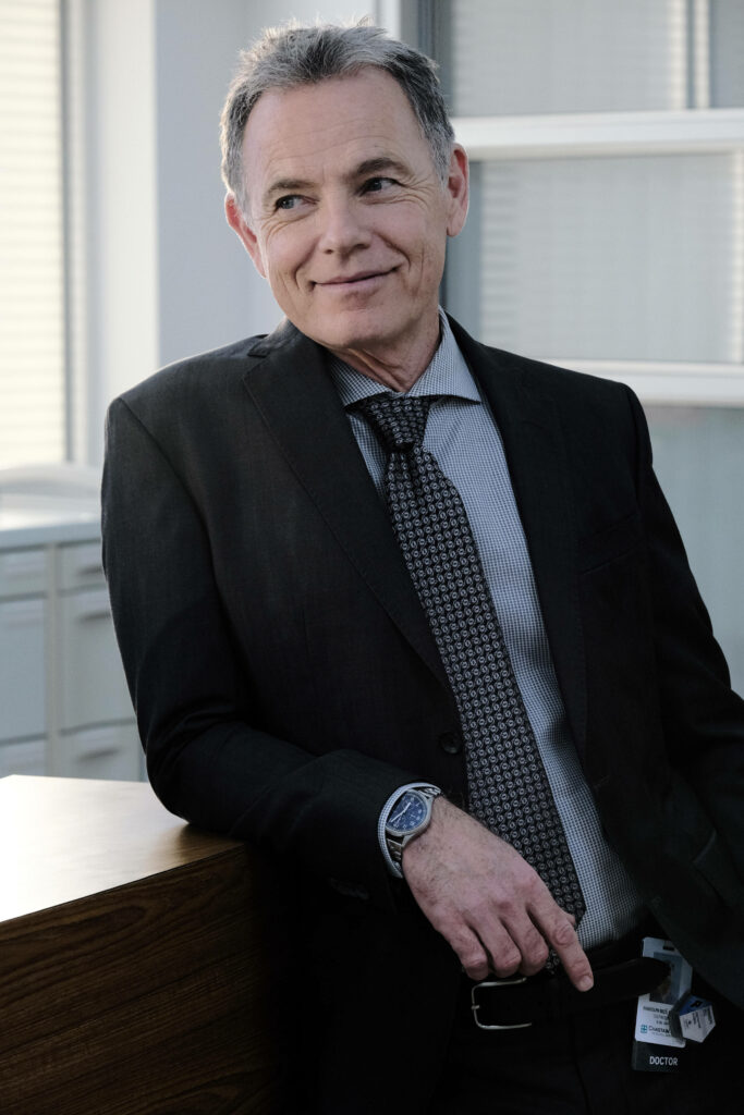 Bruce Greenwood confident professional portrait in dark suit modern office background wallpaper