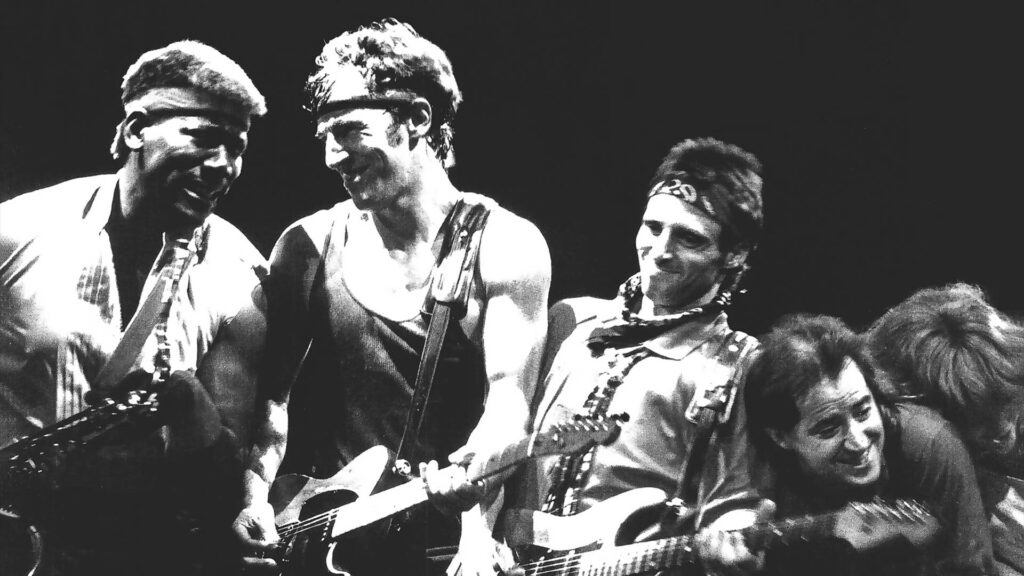Black-and-white Bruce Springsteen And E Street Band live performance wallpaper with guitars