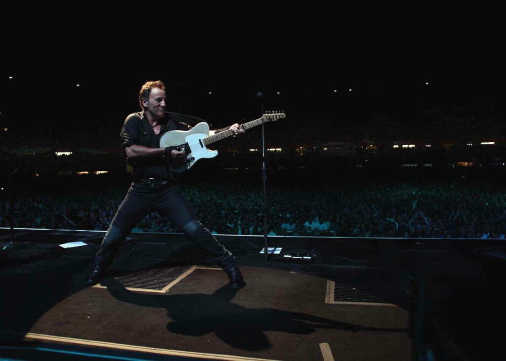 Bruce Springsteen performing live with guitar and vibrant crowd at London Calling concert wallpaper
