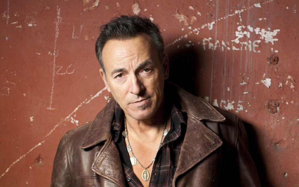 Bruce Springsteen portrait wallpaper wearing brown leather jacket flannel shirt and Miraculous Medal