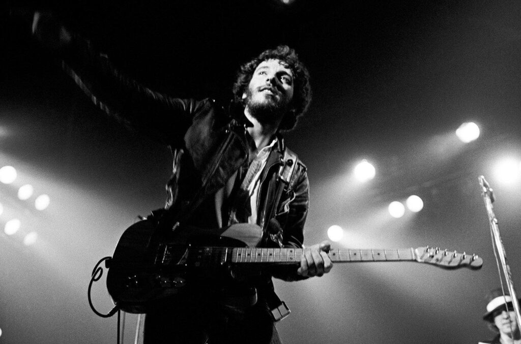 Black and white Bruce Springsteen live performance poster with vintage rock style and dramatic lighting Wallpaper