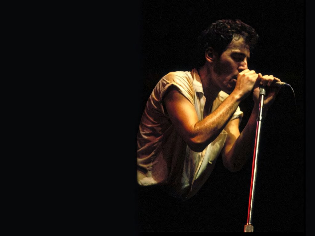 Bruce Springsteen passionately singing Someday We'll Be Together on stage with dramatic lighting Wallpaper