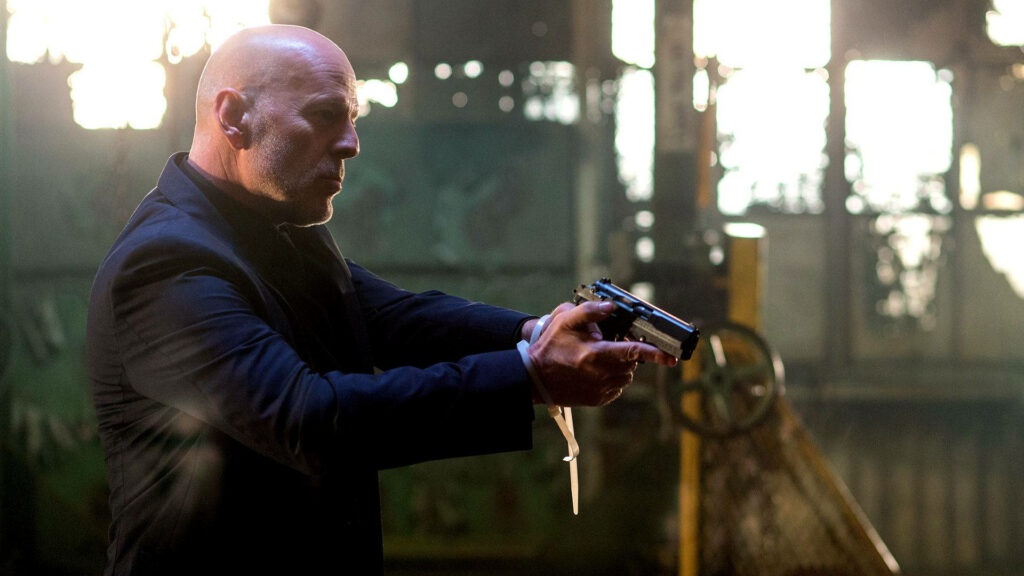 Bruce Willis intense action scene holding gun in dramatic industrial setting from Extraction wallpaper