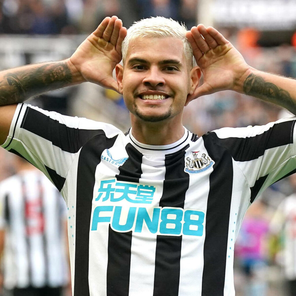 Bruno Guimarães celebrates in black and white Newcastle kit with platinum blonde hair on field Wallpaper