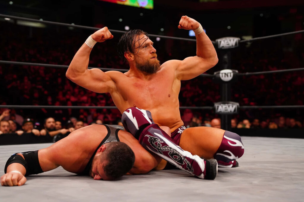 Bryan Danielson flexing muscles in AEW ring vibrant lights intense wrestling wallpaper background