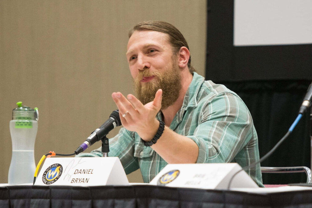 Bryan Danielson wrestler speaking at panel in green plaid shirt natural light conference wallpaper