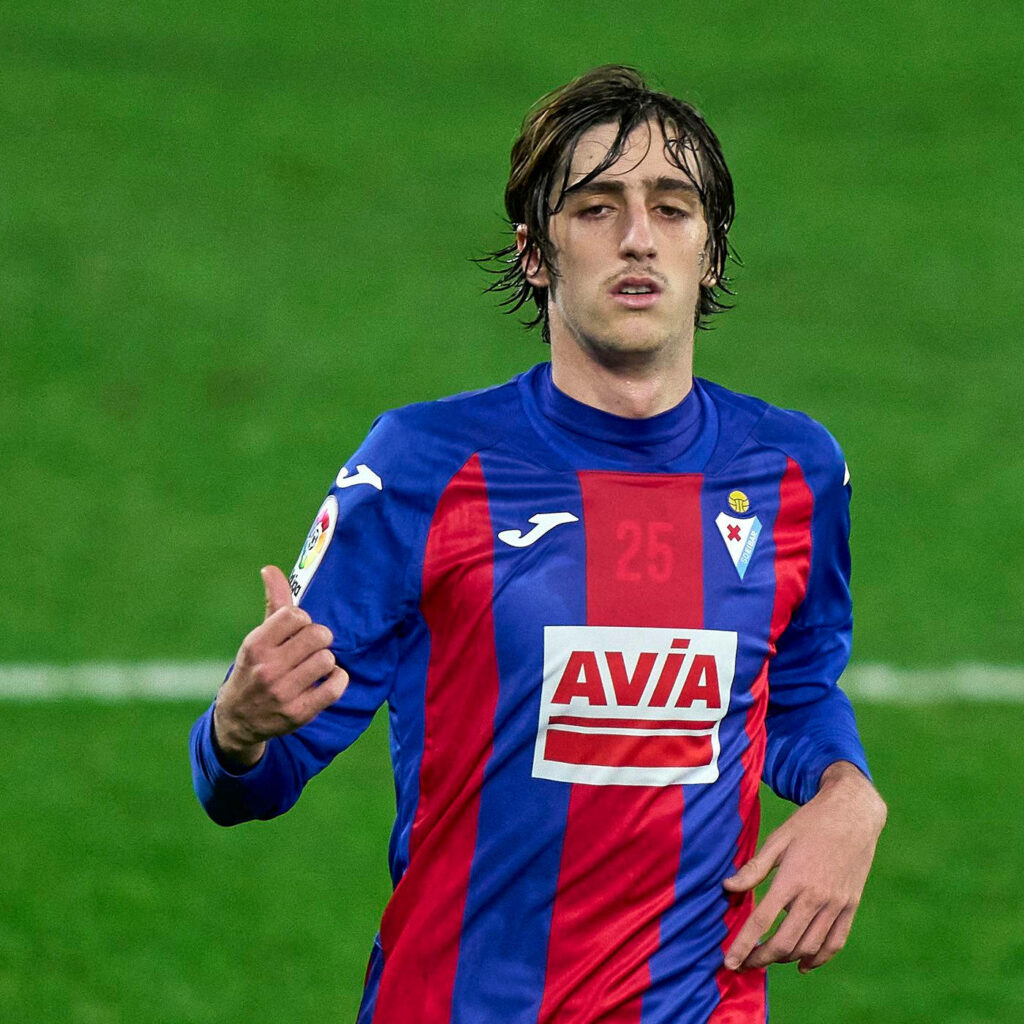 Bryan Gil in blue red Eibar jersey on green pitch dynamic soccer action football wallpaper background