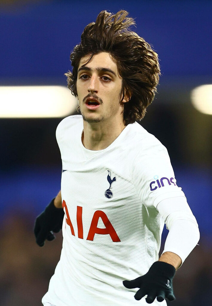Bryan Gil sprinting in Tottenham Hotspur kit inside vibrant football stadium Premier League action Wallpaper