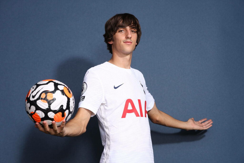 Bryan Gil in white Tottenham Hotspur kit holding Premier League ball on blue background wallpaper