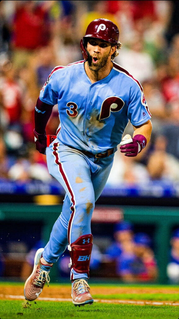 Bryce Harper in retro Phillies uniform and red cap running on field baseball wallpaper background