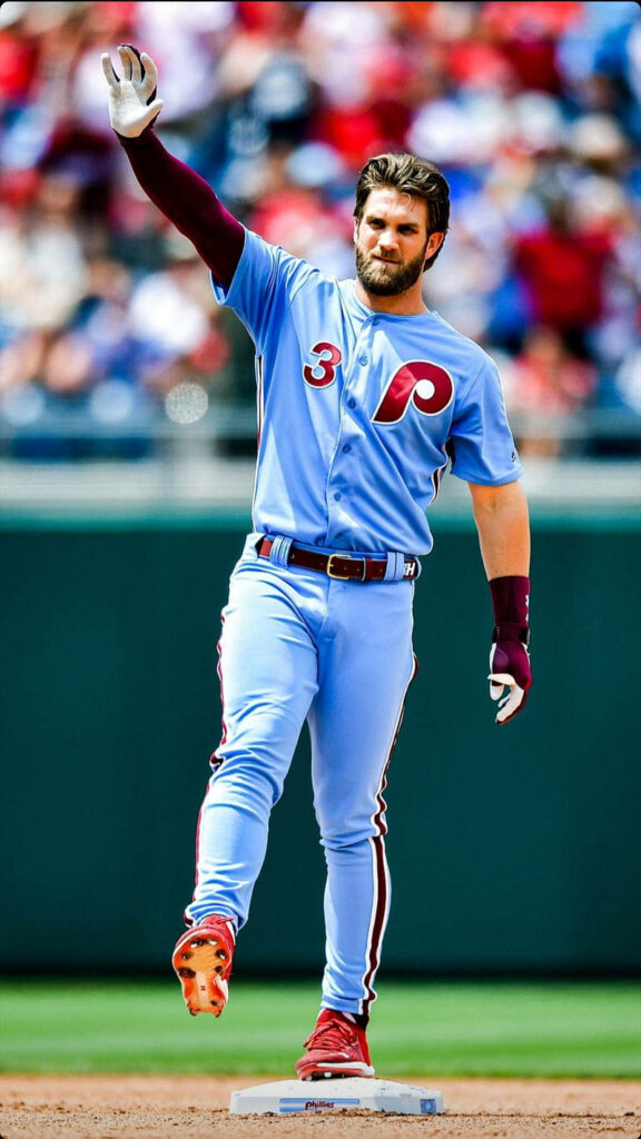Bryce Harper Phillies baseball player waving on field in light blue uniform vibrant stadium background Wallpaper