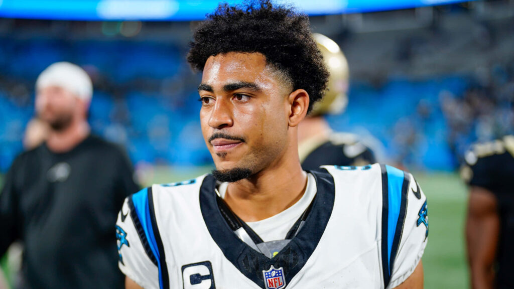 Bryce Young in Carolina Panthers uniform on field with vibrant blue stadium background wallpaper