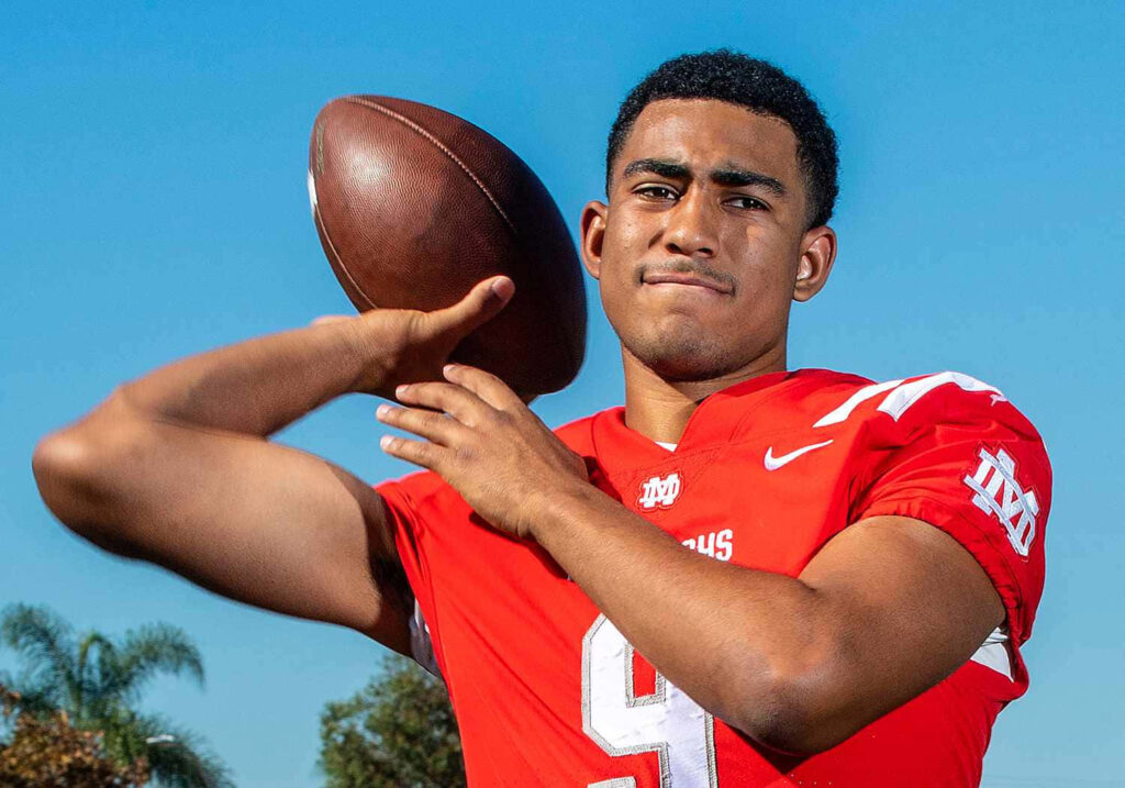 Bryce Young quarterback in red jersey throwing football under clear blue sky high-resolution portrait Wallpaper