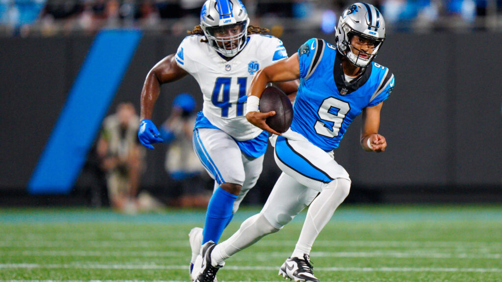 Bryce Young Panthers quarterback dodges tackle in blue black uniform NFL action stadium lights Wallpaper