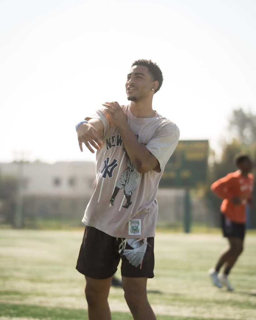 Bryce Young training outdoors in dynamic pose on grassy field with natural light in sportswear Wallpaper