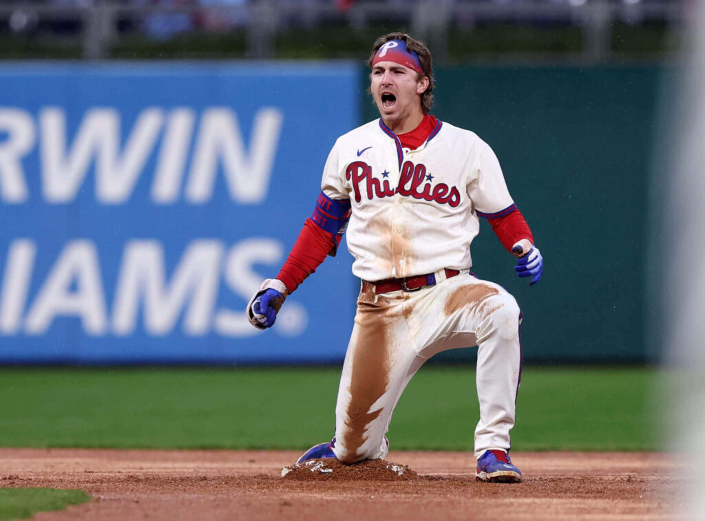 Bryson Stott Phillies celebrating on baseball field in white uniform showing victory and passion Wallpaper