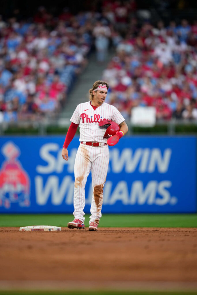 Bryson Stott Phillies infielder standing on baseball field under stadium lights with blurred crowd background Wallpaper