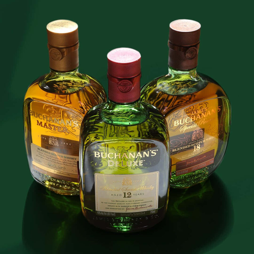 Three Buchanan's Blended Whiskey bottles Master Deluxe 12 Years Special Reserve 18 Years on green background Wallpaper