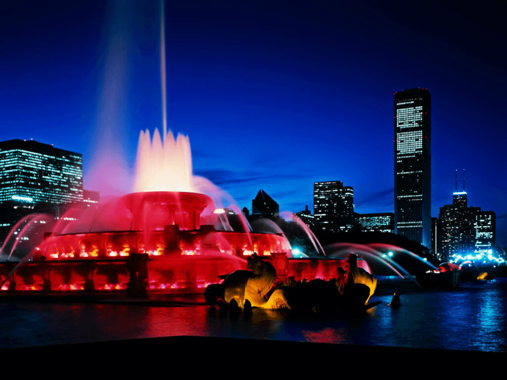 Buckingham Fountain glowing red at night with Chicago skyline and deep blue sky background Wallpaper