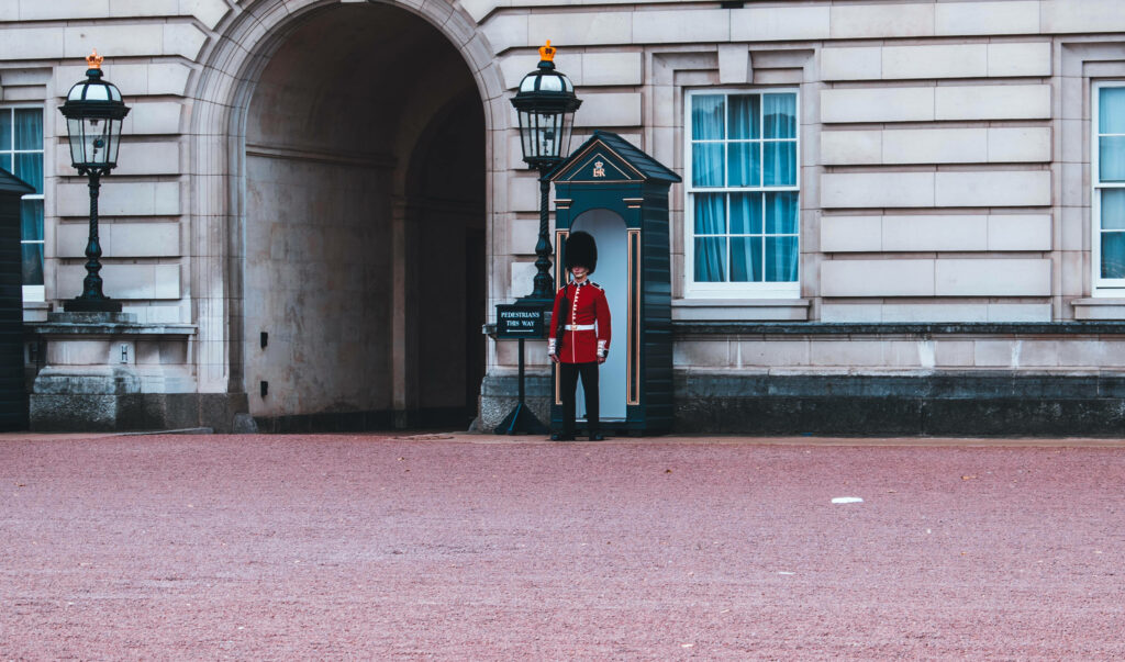 Buckingham Palace guard in red uniform and bearskin hat standing by ornate sentry box Wallpaper