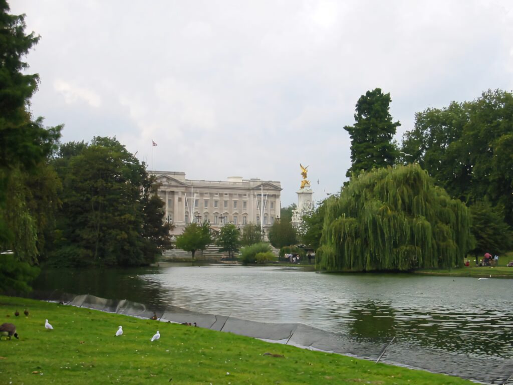 Buckingham Palace behind river with lush trees and cloudy sky iconic London landmark wallpaper