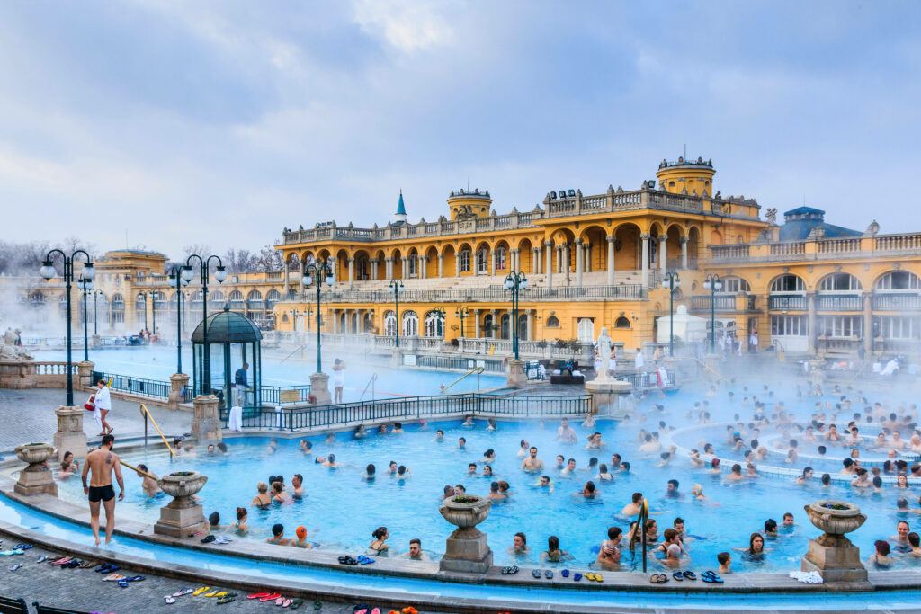 Budapest thermal spa with visitors relaxing in blue waters and historic architecture background Wallpaper
