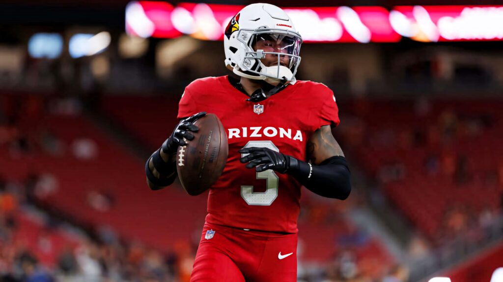 Arizona Cardinals safety Budda Baker in red uniform tackles during intense football game action Wallpaper