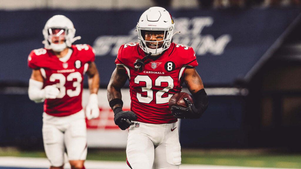 Budda Baker Arizona Cardinals intense action in red and white uniform on blurred stadium background Wallpaper
