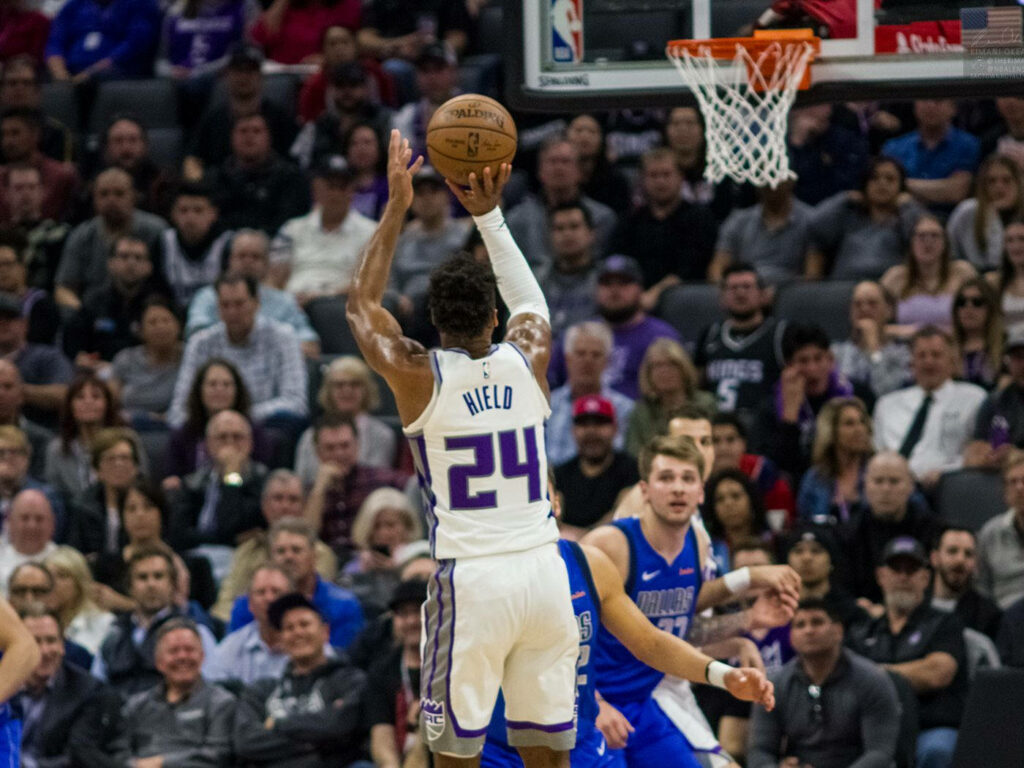Buddy Hield mid-air jump shot Sacramento Kings intense NBA game vibrant crowd wallpaper