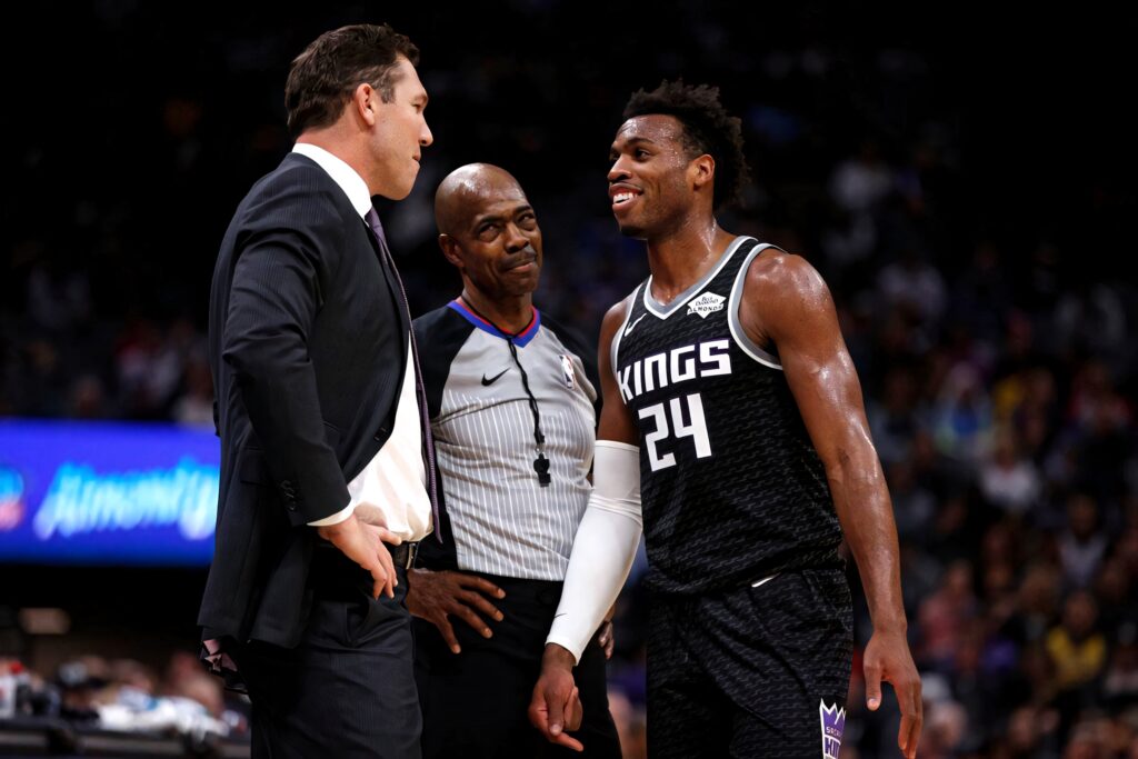Buddy Hield in Sacramento Kings jersey courtside with coach and referee during intense NBA game Wallpaper