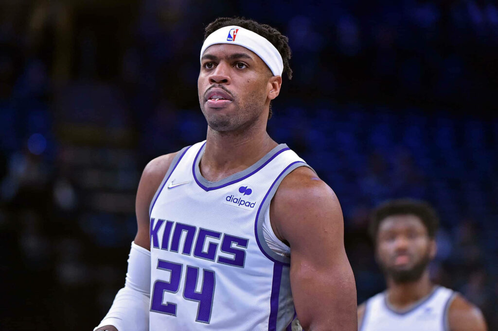 Buddy Hield Sacramento Kings focused in white purple jersey headband blue stadium background Wallpaper