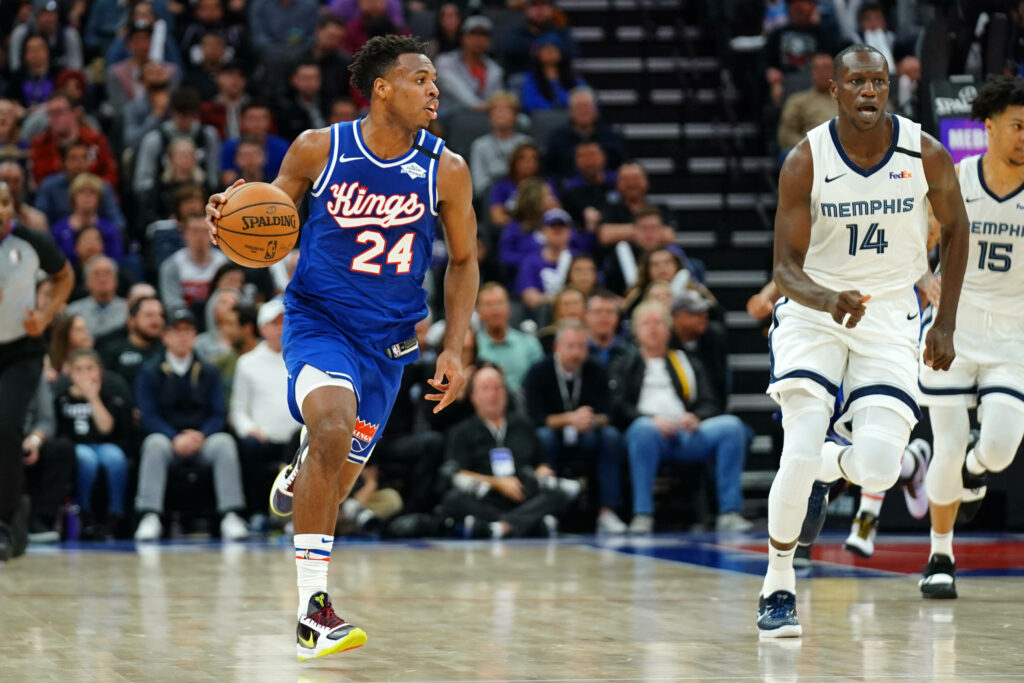 Buddy Hield Sacramento Kings dribbling in intense NBA game against Memphis Grizzlies vibrant blue uniform Wallpaper