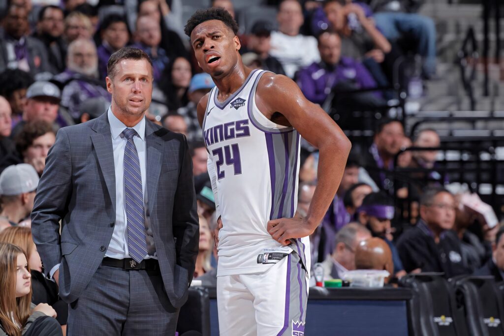 Buddy Hield in uniform with coach Dave Joerger courtside during intense Sacramento Kings game action Wallpaper